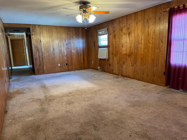 empty room featuring light colored carpet, ceiling fan, and wooden walls