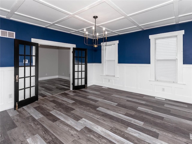 unfurnished dining area featuring a notable chandelier, dark hardwood / wood-style floors, and french doors