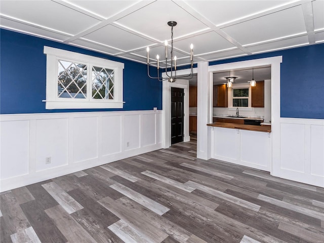 unfurnished dining area featuring hardwood / wood-style flooring, an inviting chandelier, sink, and coffered ceiling