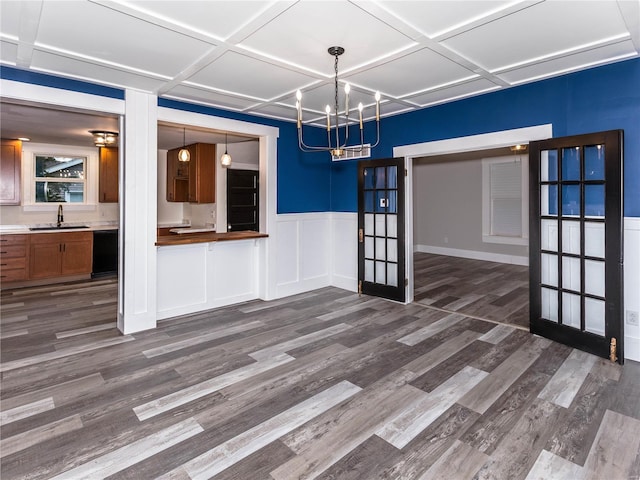 unfurnished dining area featuring coffered ceiling, dark hardwood / wood-style flooring, sink, and a chandelier