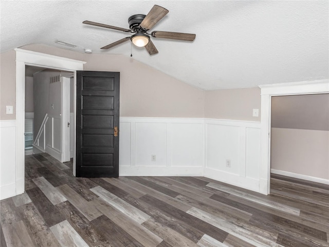 unfurnished room with a textured ceiling, dark hardwood / wood-style floors, vaulted ceiling, and ceiling fan