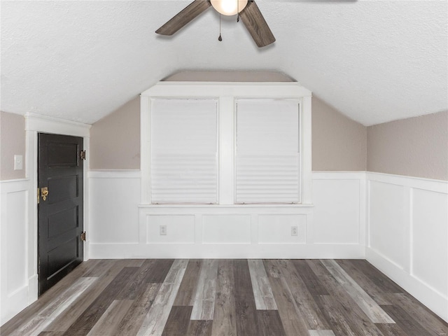 additional living space featuring a textured ceiling, ceiling fan, dark hardwood / wood-style flooring, and vaulted ceiling