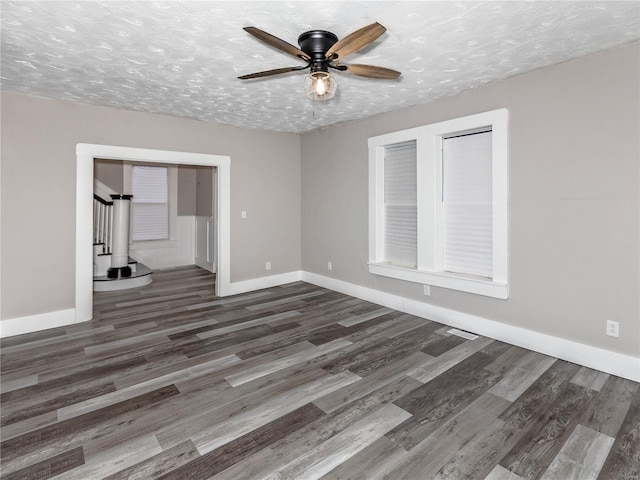 spare room with a textured ceiling, ceiling fan, and dark wood-type flooring