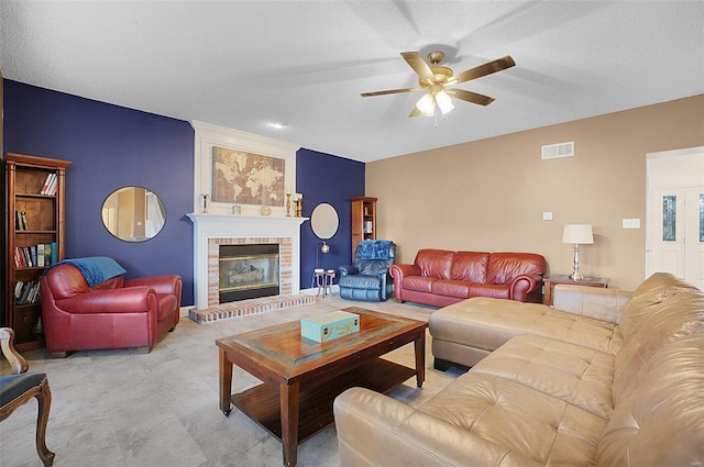 living room featuring a fireplace, a textured ceiling, and ceiling fan