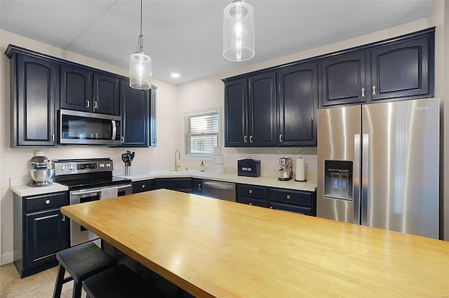 kitchen featuring decorative light fixtures, light tile patterned flooring, sink, and stainless steel appliances