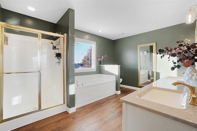 full bathroom with vanity, wood-type flooring, shower with separate bathtub, and toilet