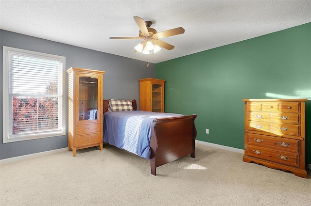 bedroom with a textured ceiling, ceiling fan, and light carpet