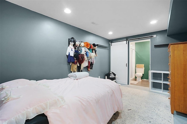 bedroom with a barn door and connected bathroom