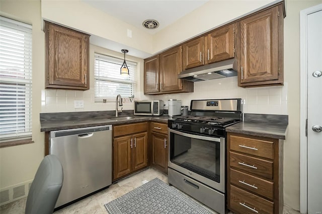 kitchen featuring backsplash, sink, decorative light fixtures, and appliances with stainless steel finishes