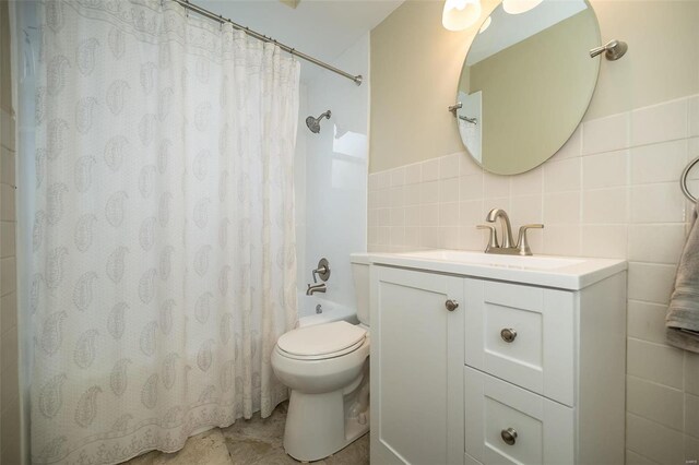 full bathroom featuring shower / bath combination with curtain, toilet, tile walls, and vanity