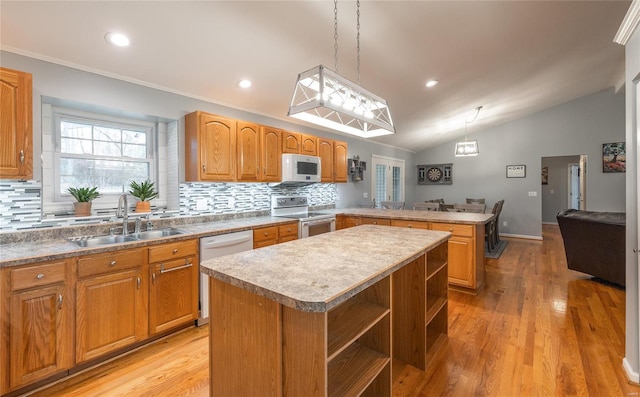 kitchen featuring a center island, sink, white appliances, and hanging light fixtures