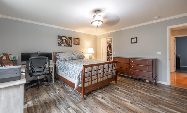 bedroom with ceiling fan, dark hardwood / wood-style flooring, crown molding, a walk in closet, and a closet