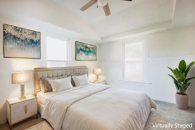 carpeted bedroom with a raised ceiling and ceiling fan