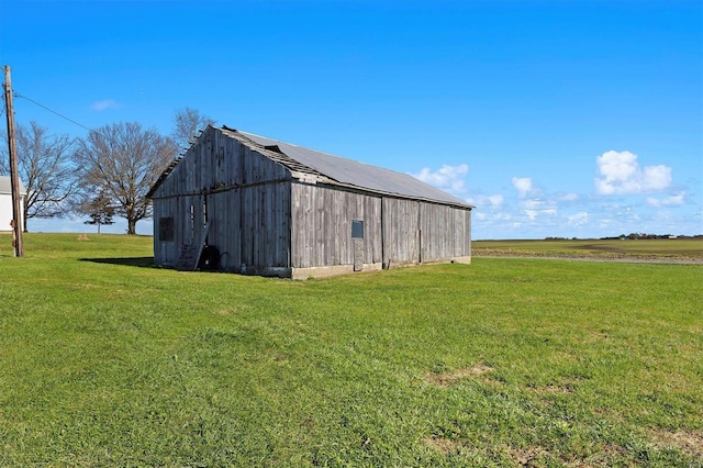 view of outbuilding featuring a rural view and a lawn