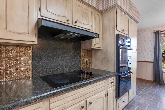 kitchen featuring light brown cabinetry, backsplash, dark stone countertops, and black appliances