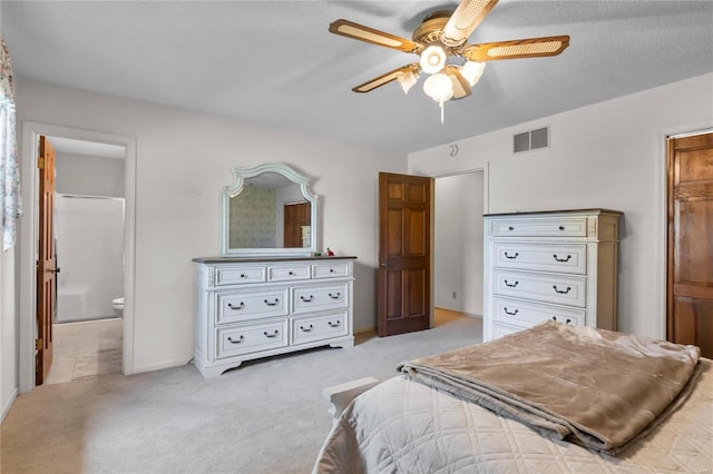 carpeted bedroom featuring a textured ceiling, ensuite bathroom, and ceiling fan