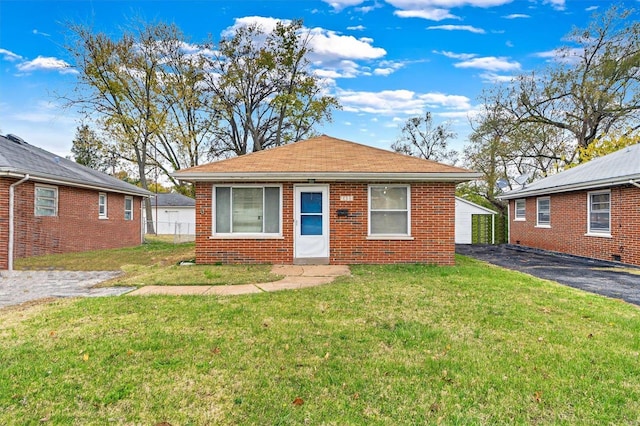 bungalow with a garage, an outdoor structure, and a front yard