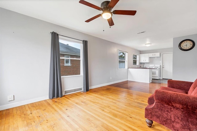 living room with light hardwood / wood-style flooring, ceiling fan, a healthy amount of sunlight, and sink