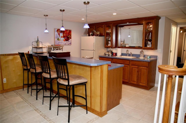 bar featuring a paneled ceiling, sink, light tile patterned flooring, and white refrigerator