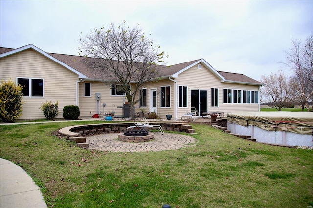 back of house featuring a fire pit, a lawn, and a covered pool