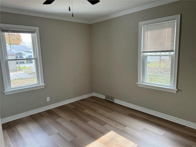 empty room featuring ceiling fan, crown molding, and light wood-type flooring