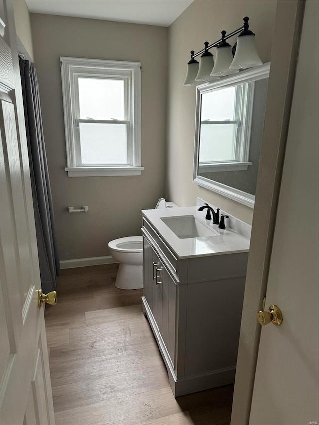 bathroom with hardwood / wood-style floors, plenty of natural light, toilet, and vanity