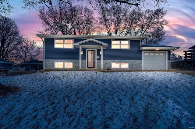 bi-level home with a garage and stone siding