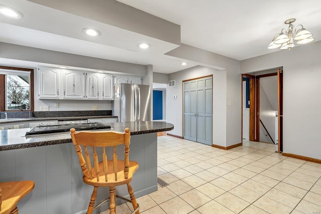 kitchen featuring light tile patterned flooring, recessed lighting, visible vents, a kitchen breakfast bar, and freestanding refrigerator