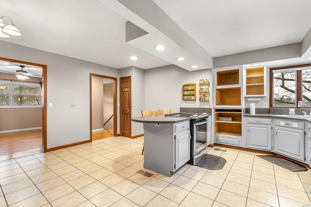 kitchen featuring a healthy amount of sunlight, stainless steel electric range oven, open shelves, and light tile patterned floors