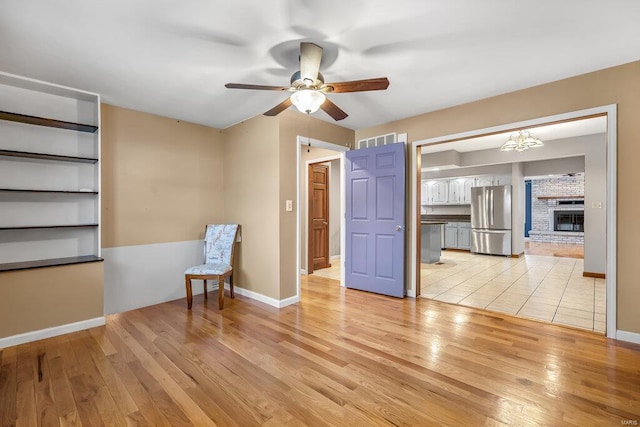 unfurnished room featuring ceiling fan, light wood-type flooring, visible vents, and baseboards