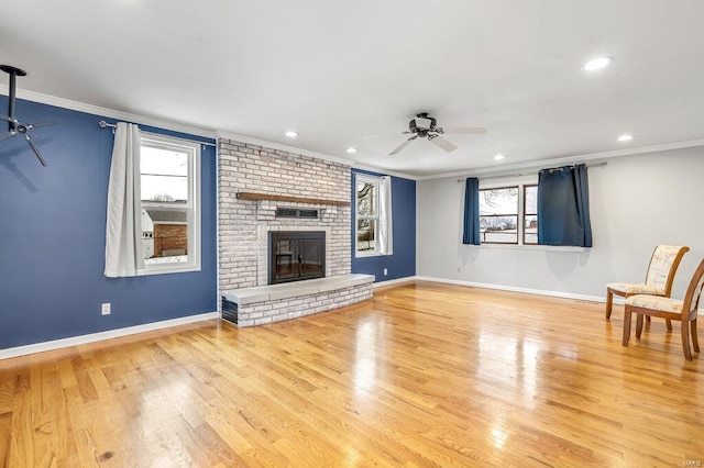 unfurnished living room with wood finished floors, a brick fireplace, crown molding, and ceiling fan