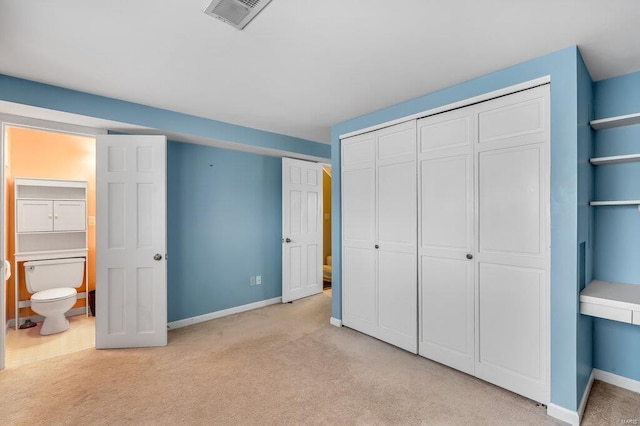 unfurnished bedroom featuring a closet, light colored carpet, visible vents, ensuite bath, and baseboards