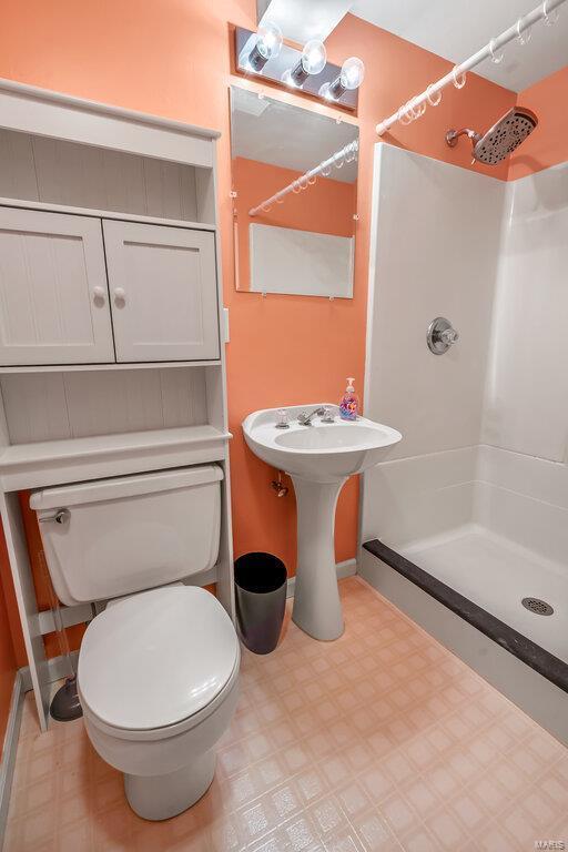 bathroom with a shower stall, toilet, and tile patterned floors