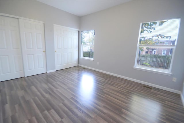 unfurnished bedroom featuring multiple closets and dark hardwood / wood-style floors