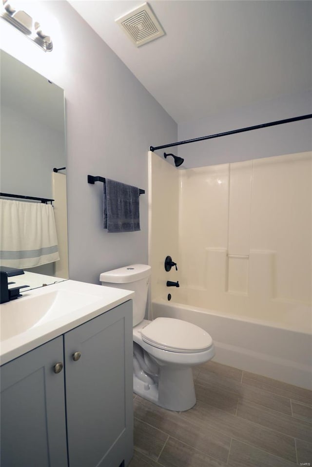 full bathroom with vanity, vaulted ceiling, shower / bathing tub combination, hardwood / wood-style floors, and toilet