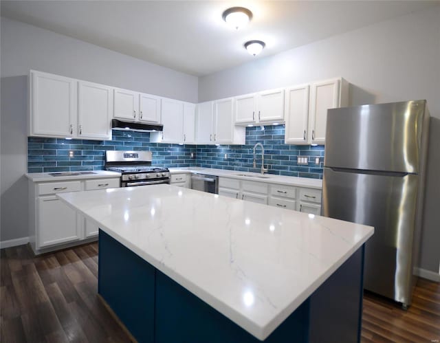 kitchen featuring white cabinets, light stone counters, appliances with stainless steel finishes, a kitchen island, and dark hardwood / wood-style flooring