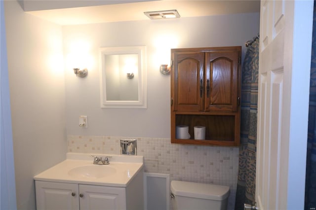 bathroom with vanity, toilet, and tile walls