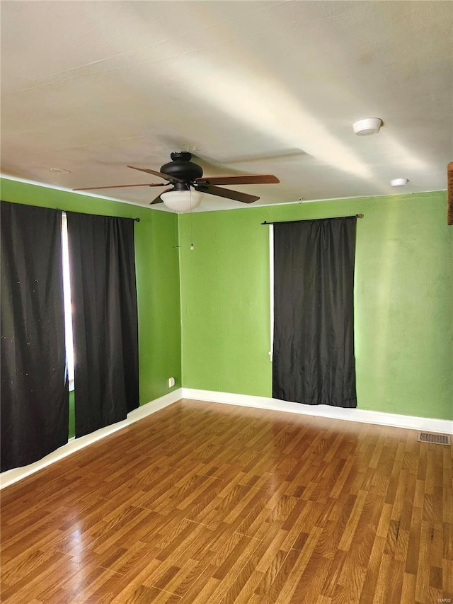 empty room with hardwood / wood-style floors and ceiling fan