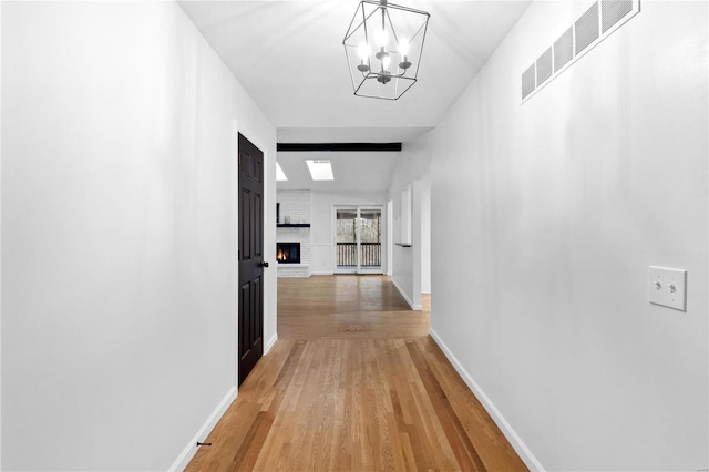 corridor with a chandelier, hardwood / wood-style floors, and lofted ceiling