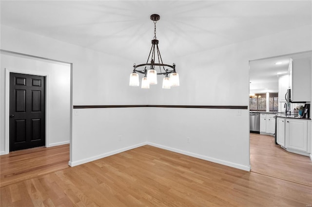 unfurnished dining area with an inviting chandelier and light hardwood / wood-style flooring