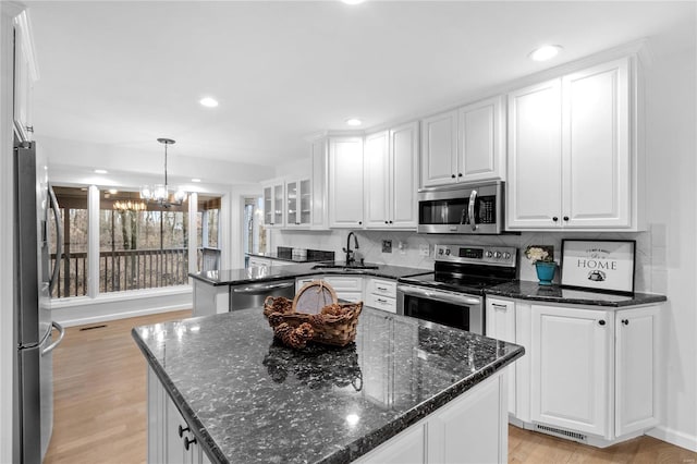 kitchen featuring pendant lighting, sink, a kitchen island, white cabinetry, and stainless steel appliances