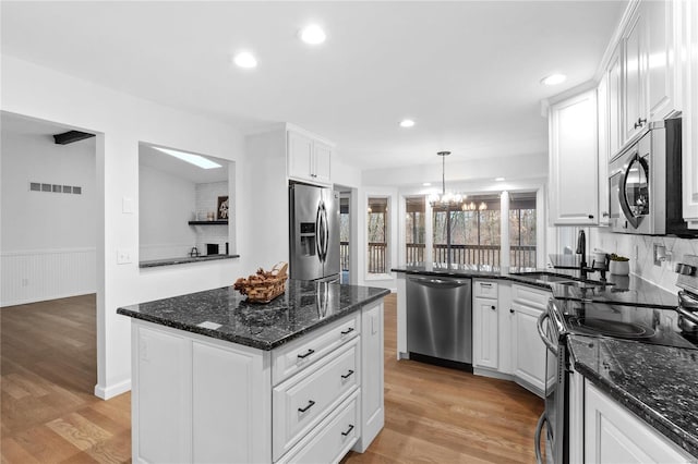 kitchen with sink, white cabinets, decorative light fixtures, and appliances with stainless steel finishes