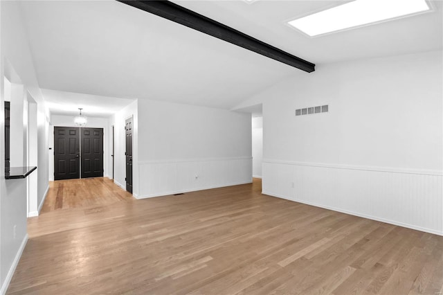 empty room with lofted ceiling with beams, light hardwood / wood-style floors, and an inviting chandelier