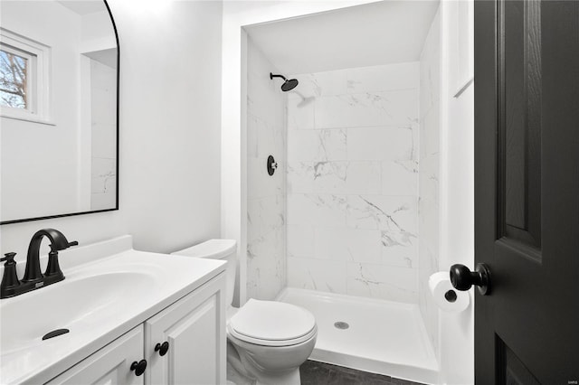 bathroom with vanity, toilet, and a tile shower