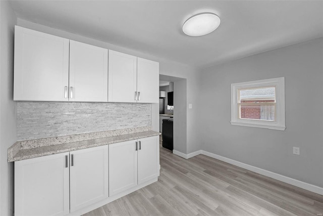 kitchen featuring light stone countertops, backsplash, light hardwood / wood-style flooring, and white cabinetry