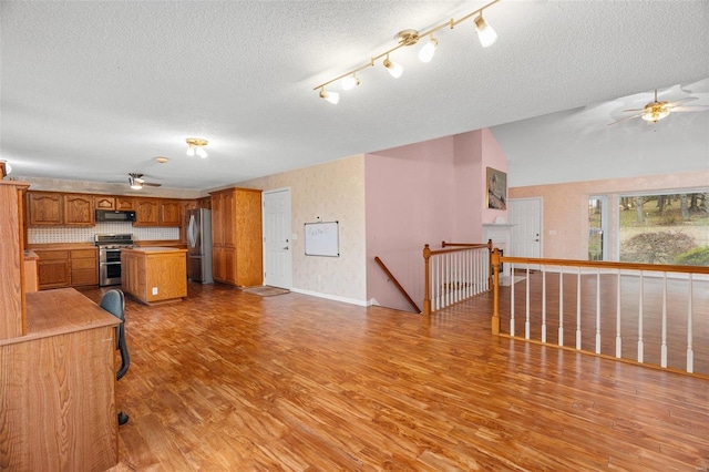 kitchen featuring appliances with stainless steel finishes, a textured ceiling, light hardwood / wood-style flooring, and lofted ceiling