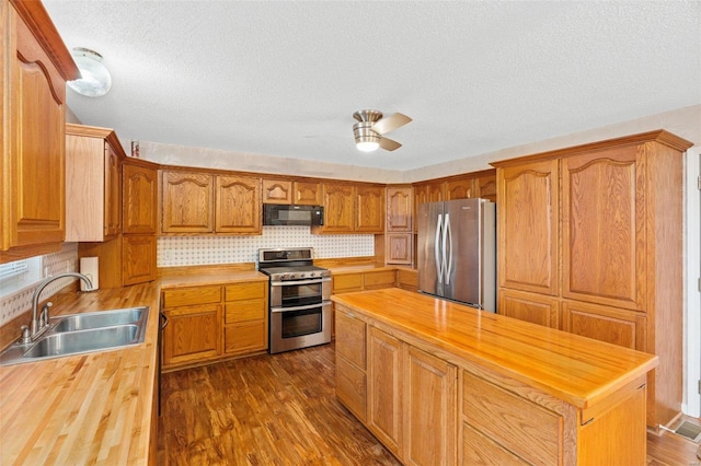 kitchen featuring sink, dark wood-type flooring, wooden counters, a textured ceiling, and appliances with stainless steel finishes