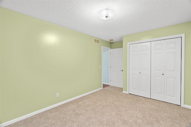 unfurnished bedroom with a textured ceiling, light colored carpet, and a closet