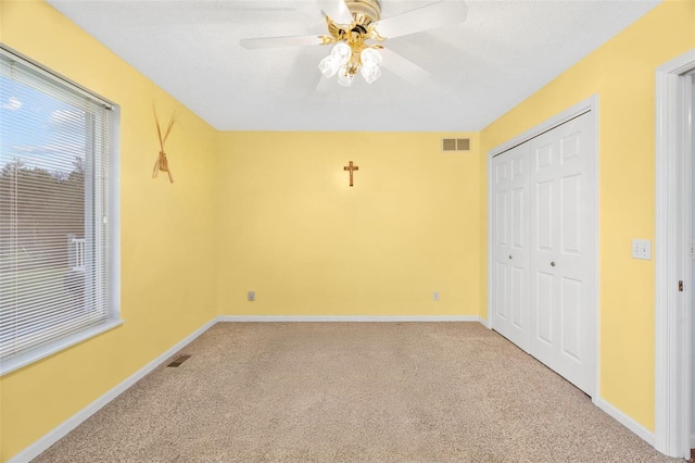 unfurnished bedroom with ceiling fan, carpet floors, a textured ceiling, and a closet