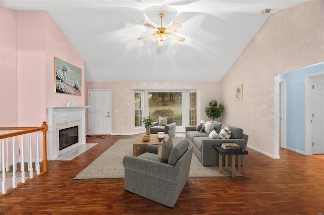 living room with vaulted ceiling, a ceiling fan, wood finished floors, wallpapered walls, and a fireplace